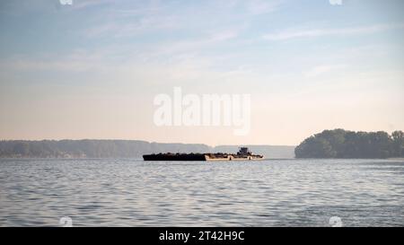 Un rimorchiatore spinge chiatte combinate caricate di sabbia lungo il Danubio Foto Stock