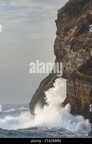 Una scenografica scena di onde potenti che si infrangono su una costa rocciosa lungo l'oceano costiero Foto Stock