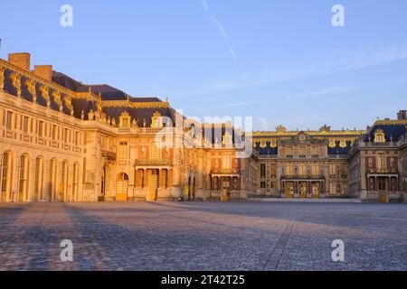Versailles: Facciata anteriore (facciata est e cortile) del palazzo arancione brillante subito dopo l'alba a Versailles, Ile-de-France, Francia Foto Stock