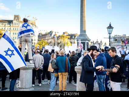 Trafalgar Square Londra. Nel bel mezzo di una grande manifestazione sul conflitto israelo-palestinese, un ebreo ortodosso aiuta un giovane "laico" Tefillin Foto Stock