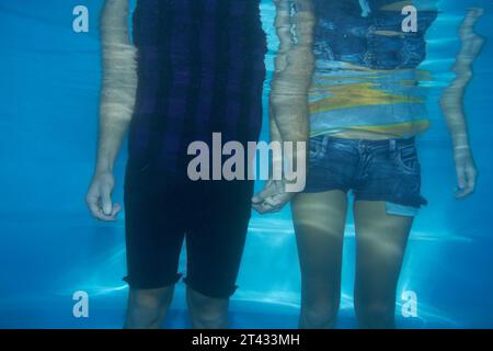 Coppia, vestiti o piscina subacquea o moda, stile alla moda o tenersi per mano. Abiti da uomo, da donna o da relazione divertenti e divertenti per l'estate Foto Stock