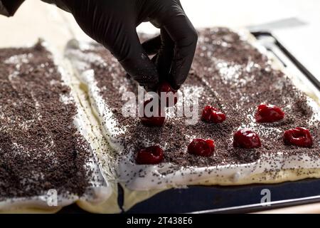 Processo di preparazione di una torta Napoleone con semi di papavero e ciliegie. Primo piano Foto Stock