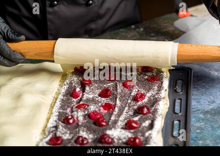 Processo di preparazione di una torta Napoleone con semi di papavero e ciliegie. Primo piano Foto Stock