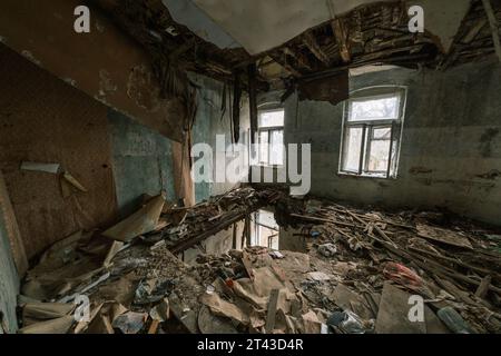 Dall'alto dell'interno della spaziosa sala con vetrate mucchio di macerie con mobili danneggiati sul pavimento con grande buco mentre la decorazione interna del soffitto distrutta, mostrando tavole appese danneggiate Foto Stock