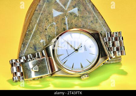 Orologio da polso Rolex Oyster dorato su sfondo giallo sabbia e piramide in pietra Foto Stock
