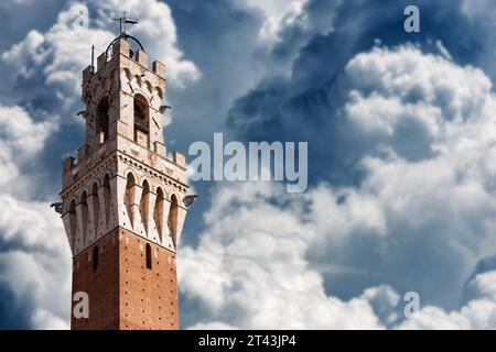 Primo piano della Torre del Mangia in Piazza del campo nel centro di Siena, Toscana, Italia, Europa. Contro un cielo con la bella cumulus clo Foto Stock