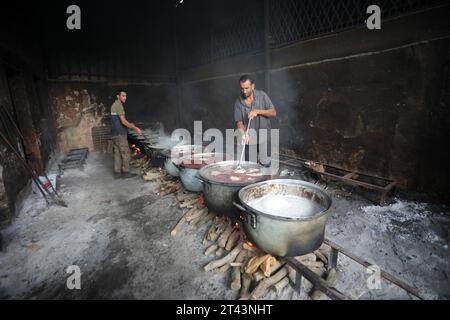 Gli uomini palestinesi preparano il cibo in grandi pentole bollenti su fuochi di legno a causa della mancanza di gas di cottura, che sarà distribuito alle famiglie sfollate in seguito alla richiesta di Israele di più di un milione di residenti nella parte settentrionale di Gaza di trasferirsi a sud, a Rafah, nella striscia meridionale di Gaza sabato 28 ottobre 2023. Lo sciopero israeliano continua a Gaza in mezzo alla carenza di forniture mediche, acqua e spegnimento, ma gli attacchi aerei israeliani hanno causato danni sostanziali alle infrastrutture sul lato palestinese. Foto di Ismael Mohamad/UPI. Foto Stock