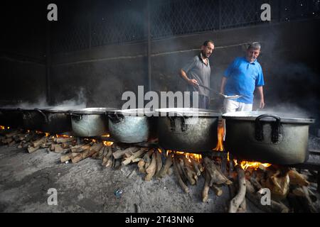 Gli uomini palestinesi preparano il cibo in grandi pentole bollenti su fuochi di legno a causa della mancanza di gas di cottura, che sarà distribuito alle famiglie sfollate in seguito alla richiesta di Israele di più di un milione di residenti nella parte settentrionale di Gaza di trasferirsi a sud, a Rafah, nella striscia meridionale di Gaza sabato 28 ottobre 2023. Lo sciopero israeliano continua a Gaza in mezzo alla carenza di forniture mediche, acqua e spegnimento, ma gli attacchi aerei israeliani hanno causato danni sostanziali alle infrastrutture sul lato palestinese. Foto di Ismael Mohamad/UPI. Foto Stock