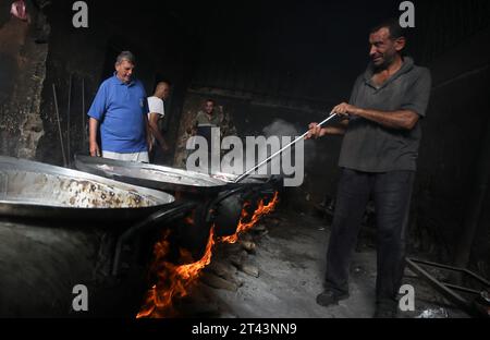 Gli uomini palestinesi preparano il cibo in grandi pentole bollenti su fuochi di legno a causa della mancanza di gas di cottura, che sarà distribuito alle famiglie sfollate in seguito alla richiesta di Israele di più di un milione di residenti nella parte settentrionale di Gaza di trasferirsi a sud, a Rafah, nella striscia meridionale di Gaza sabato 28 ottobre 2023. Lo sciopero israeliano continua a Gaza in mezzo alla carenza di forniture mediche, acqua e spegnimento, ma gli attacchi aerei israeliani hanno causato danni sostanziali alle infrastrutture sul lato palestinese. Foto di Ismael Mohamad/UPI. Foto Stock