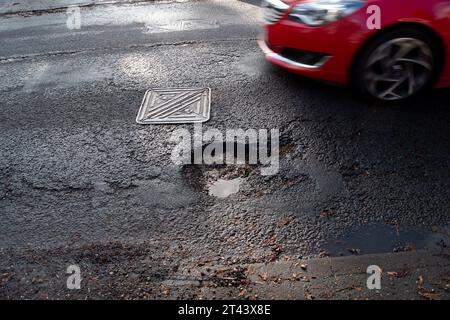 Dorney, Buckinghamshire, Regno Unito. 27 ottobre 2023. Una delle molte buche della strada nel Dorney Village, Buckinghamshire, in attesa di essere riparata dal Consiglio del Buckinghamshire. Molte delle strade del Buckinghamshire sono ancora in cattivo stato di riparazione. Credito: Maureen McLean/Alamy Foto Stock