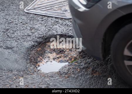 Dorney, Buckinghamshire, Regno Unito. 27 ottobre 2023. Una delle molte buche della strada nel Dorney Village, Buckinghamshire, in attesa di essere riparata dal Consiglio del Buckinghamshire. Molte delle strade del Buckinghamshire sono ancora in cattivo stato di riparazione. Credito: Maureen McLean/Alamy Foto Stock