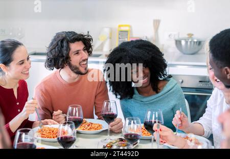 Amici multietnici che si riuniscono per pranzare con cibo italiano Foto Stock