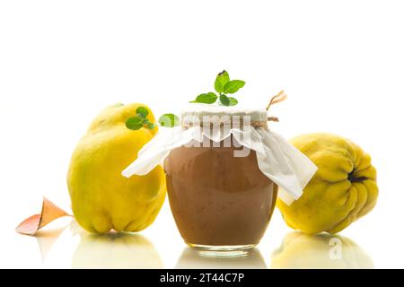 Frutti di cotogna maturi con marmellata in un vaso di vetro isolato su sfondo bianco. Ricette autunnali. Foto Stock