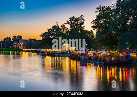 Wroclaw, Polonia - giugno 25 2023: Facciate di bar e ristoranti moderni sull'acqua vicino all'isola e piene di piccole luci accese intorno Foto Stock