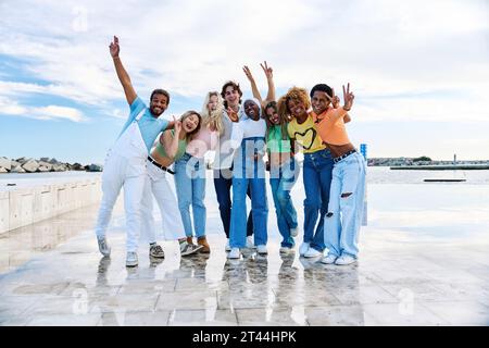 Felici amici multietnici che alzano le mani e gestiscono la pace all'aperto Foto Stock
