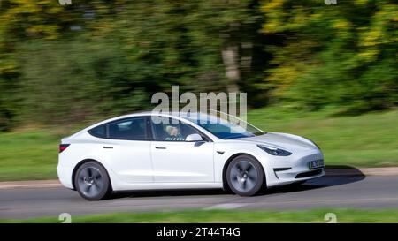 Milton Keynes, Regno Unito - 28 ottobre 2023:2020 auto elettrica Tesla Model 3 bianca che guida su una strada inglese Foto Stock