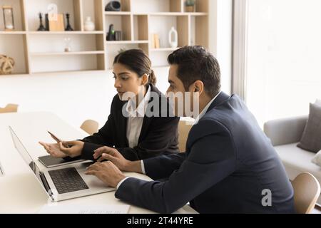 Due colleghi professionisti indiani concentrati che discutono di applicazioni online Foto Stock