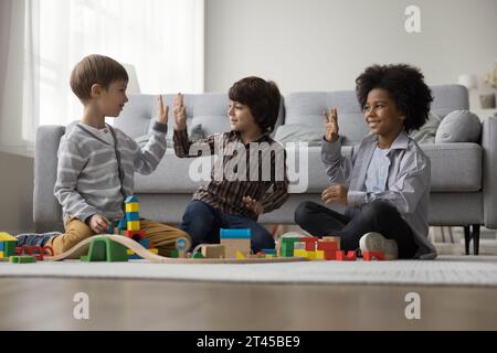 I piccoli ragazzi giocano insieme con la ferrovia in legno in un accogliente soggiorno Foto Stock