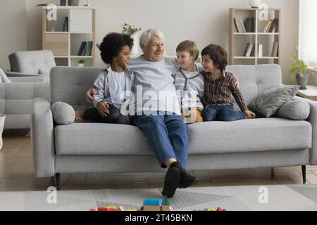 Il bisnonno in pensione parla con tre bisnipoti multietnici Foto Stock