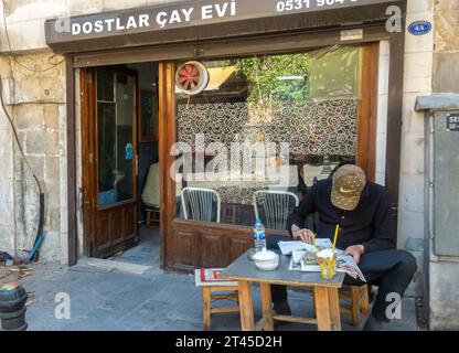 Gaziantep Turkey: Uomo che legge il giornale nella tradizionale casa da tè, chai Diner, chai Cafe' con tavoli all'aperto. Foto Stock