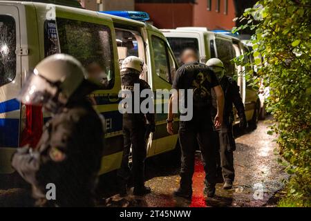 Gelsenkirchen, Germania. 28 ottobre 2023. Un uomo che indossa una maglietta con la scritta 'Pitbull' viene perquisito dalla polizia. La polizia ha posto fine a un evento di sospetti sostenitori della scena di destra a Gelsenkirchen. Secondo i primi risultati della polizia, circa 80 persone si erano riunite il sabato sera in un circolo di un giardino per un concerto. Credito: Christoph Reichwein/dpa/Alamy Live News Foto Stock