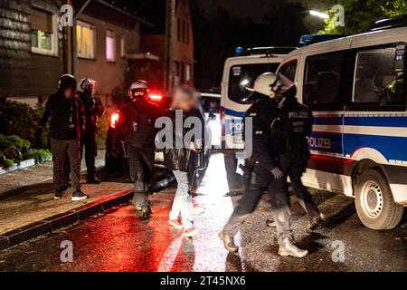 Gelsenkirchen, Germania. 28 ottobre 2023. Una donna viene portata su un veicolo della polizia dalla polizia per essere identificata. La polizia ha posto fine a un evento di sospetti sostenitori della scena di destra a Gelsenkirchen. Secondo i primi risultati della polizia, circa 80 persone si erano riunite il sabato sera in un circolo di un giardino per un concerto. Credito: Christoph Reichwein/dpa/Alamy Live News Foto Stock