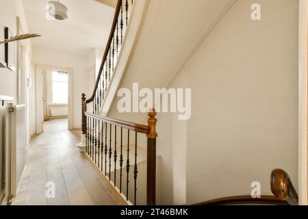 una scala in una casa con pareti bianche e pavimento in legno duro le scale sono fatte di tavole di legno Foto Stock