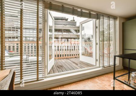 una camera con pavimento in legno e porte scorrevoli in vetro che si affacciano sulla città dall'interno Foto Stock
