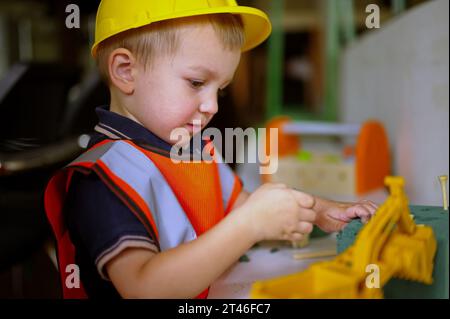 Piccolo bambino vestito da muratore che gioca a casa Foto Stock