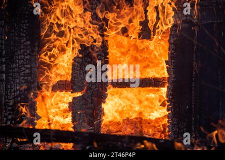 Una casa di legno in fiamme. Fuoco della casa. Edificio in fiamme. Fiamme libere. Fuoco in casa. 911 concetto. Incendio di sicurezza. incendio della struttura completamente inghiottita. Foto Stock