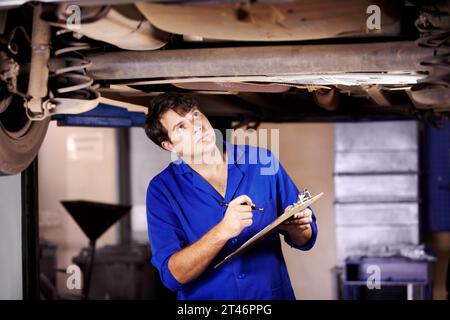 Auto, ispezione o assistenza con un meccanico in un garage per una relazione sulla riparazione di un veicolo a fini assicurativi. Manutenzione, professionalità ed esperienza Foto Stock