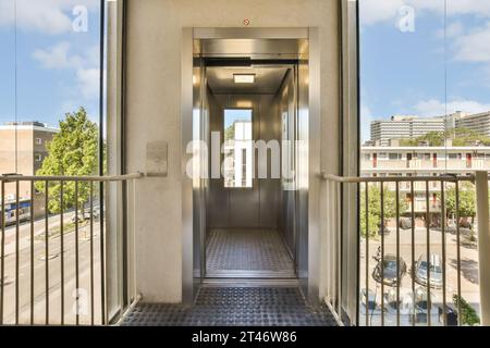 un ascensore in un edificio con cielo blu e nuvole bianche dietro le porte è aperto per consentire l'accesso alle persone Foto Stock