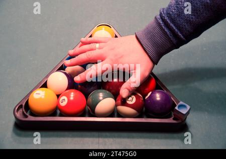 Palline da biliardo sul tavolo da biliardo verde con la mano di un giocatore sopra di loro Foto Stock