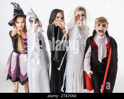 Buon Halloween partito con i bambini trucco o trattando in diversi costumi fantasma, vampiro, scheletro, strega Foto Stock