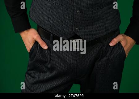 primo piano cromakey con sfondo verde, capelli scuri, giovane uomo. Una mano da uomo nella tasca di eleganti pantaloni grigi da primo piano su sfondo bianco. Giovane uomo di successo, uomo d'affari, imprenditore Foto Stock