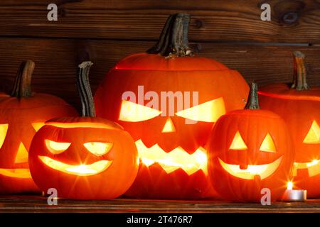 Tre lanterne in zucca di Halloween e candele accese su sfondo di legno scuro Foto Stock