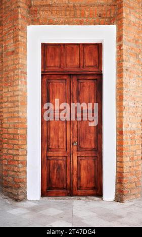 Vecchia porta di legno in un muro di mattoni, Otavalo, Ecuador. Foto Stock