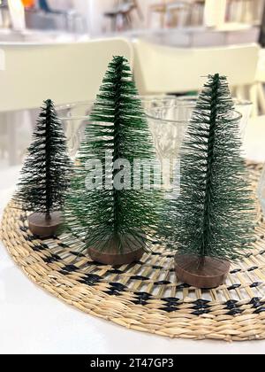 natale, piccoli noel o alberi di natale sul tavolo con attenzione selettiva. tre alberi di pino sul tavolo in un negozio o caffetteria decorati per noel o capodanno Foto Stock