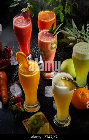 Una foto di diverse tazze di vari succhi naturali su sfondo nero, ananas, carota, succo d'arancia e mela Foto Stock