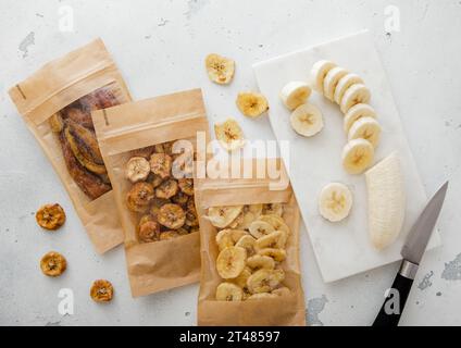 Varie fette di banana croccanti e tagliate con banana sbucciata su tavola leggera. Foto Stock