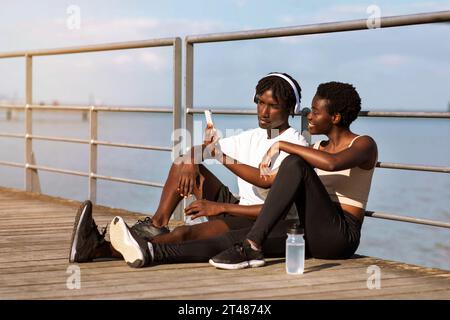 App fitness. Giovane coppia nera motivata che controlla la propria attività sportiva sullo smartphone Foto Stock