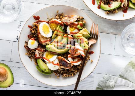 Una ciotola proteica sana con uova sode e pollo, condita con avocado. Foto Stock