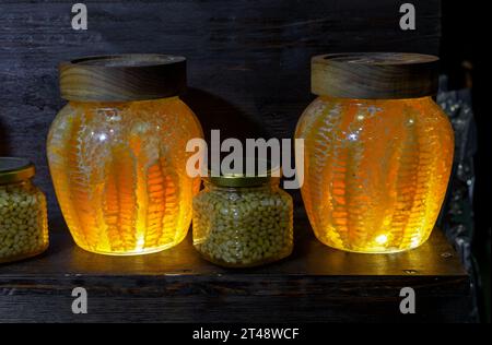 Miele in favi in vasetti di vetro con splendida illuminazione sulla vetrina di un negozio. Foto Stock
