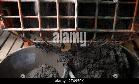 Il processo di versamento manuale di una fondazione. La soluzione viene versata in un secchio da una betoniera. La soluzione di calcestruzzo finita viene versata Foto Stock