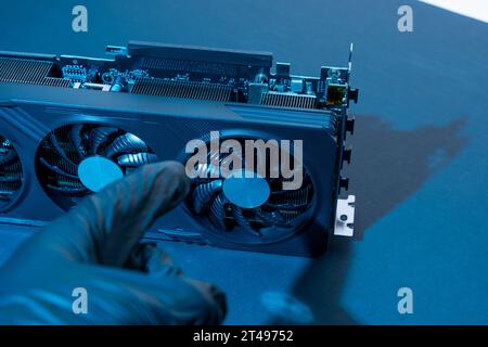 la mano di un tecnico informatico contiene una potente e moderna scheda per videogiochi per un computer con tre fan. Il concetto di hardware per PC. Video car di gioco Foto Stock