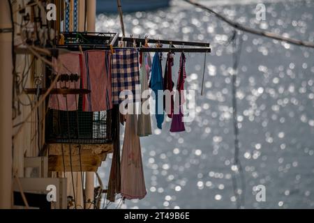 Lo scintillante Mediterraneo scintilla mentre il lavaggio si asciuga in primo piano su un appendiabiti a Malta Foto Stock