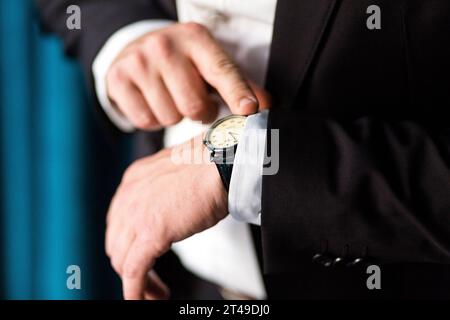 L'uomo regola il tempo sull'orologio da polso, simboleggiando precisione ed eleganza. Foto Stock