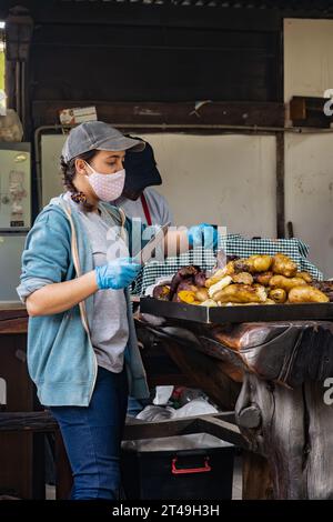 COLONIA SUIZA, SAN CARLOS DE BARILOCHE, ARGENTINA - 10 NOVEMBRE 2021: Una donna mette da parte verdure preparate sottoterra come parte del curanto Foto Stock