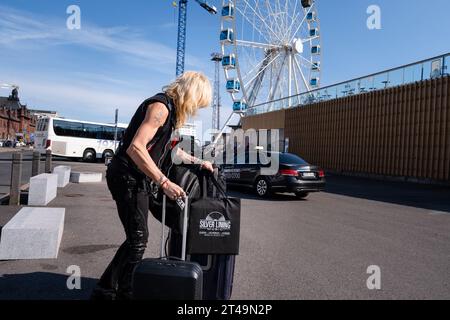 L'icona heavy metal finlandese Michael Monroe di Hanoi Rocks esce da un taxi con valigie e una borsa in vinile in estate nel centro di Helsinki, Finlandia. Foto Stock