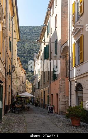 Via San Rocco, vicolo stretto nel borgo medievale con sullo sfondo in primavera il promontorio di Caprazoppa, Finalborgo, finale Ligure, Savona Foto Stock